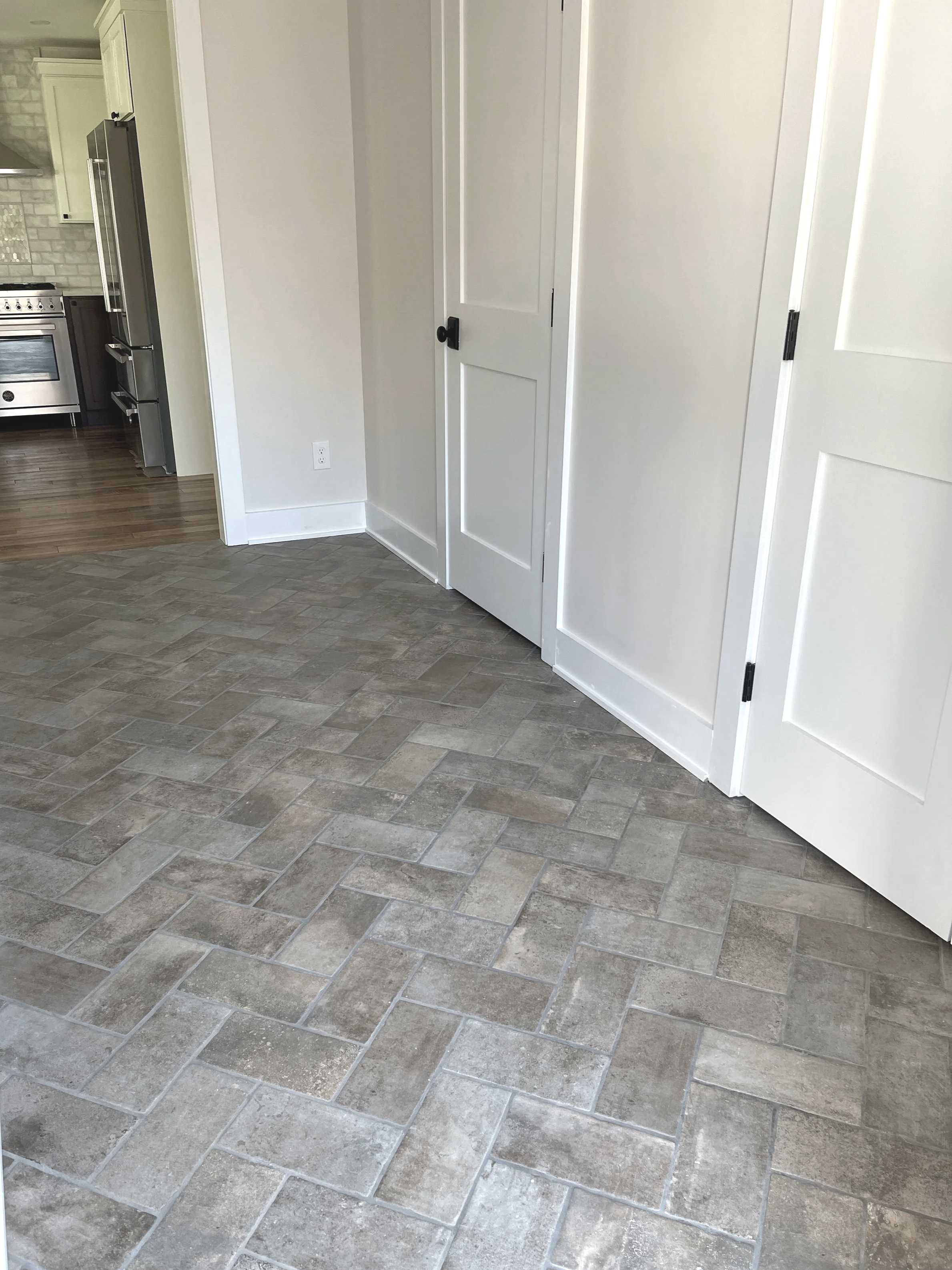 Gray weathered brick herringbone floor in a mud room hallway, designed and photographed by Sara Trotter / Chroma Maison Design.