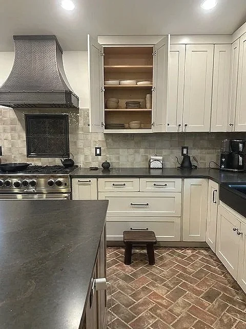 Farmhouse kitchen with open cabinet doors, a copper hood fan above a Blue Star range, and Inglenook herringbone floor tile, designed and photographed by Sara Trotter / Chroma Maison Design. 