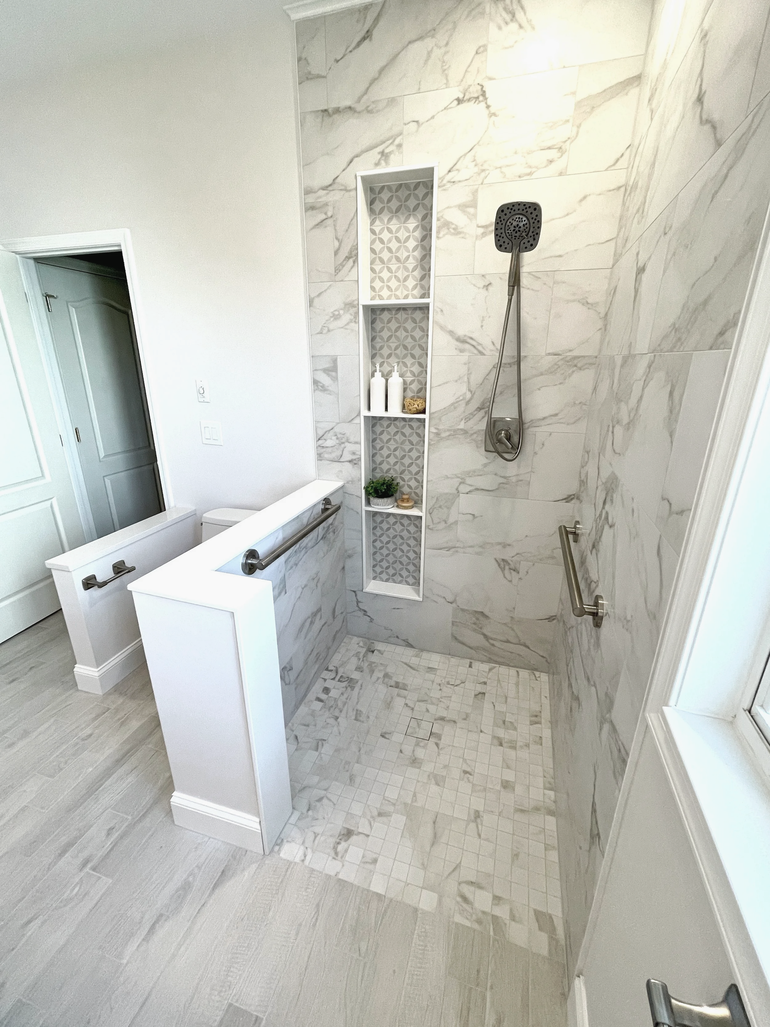 55+ community bathroom remodel with a curb less entry shower showcasing a long linear pattern niche box for a dramatic effect, designed and photographed by Sara Trotter / Chroma Maison Design.