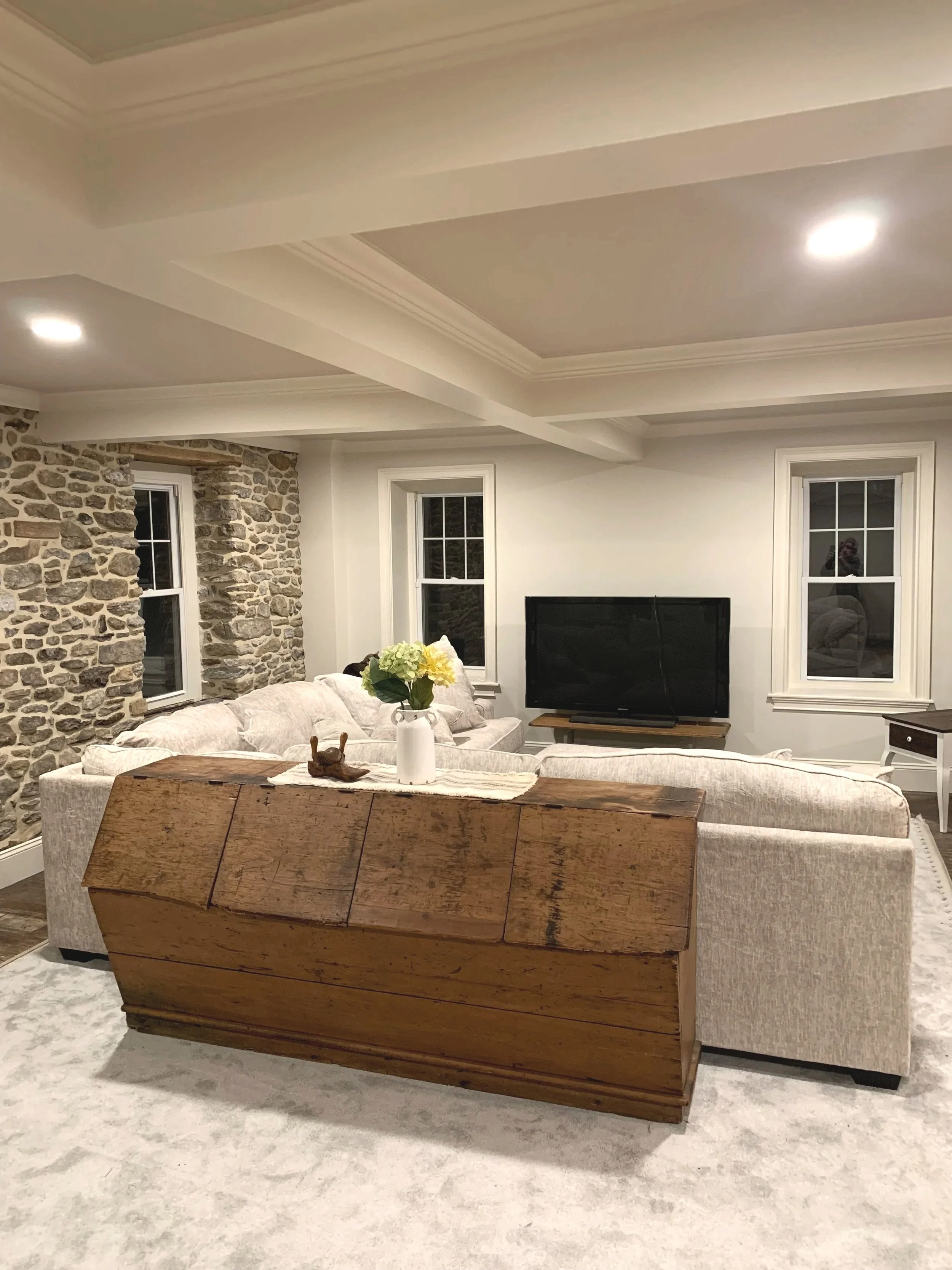 Rustic living room featuring an original stone accent wall and accent tray ceiling.  Custom paint plan and photograph by Sara Trotter / Chroma Maison Design.