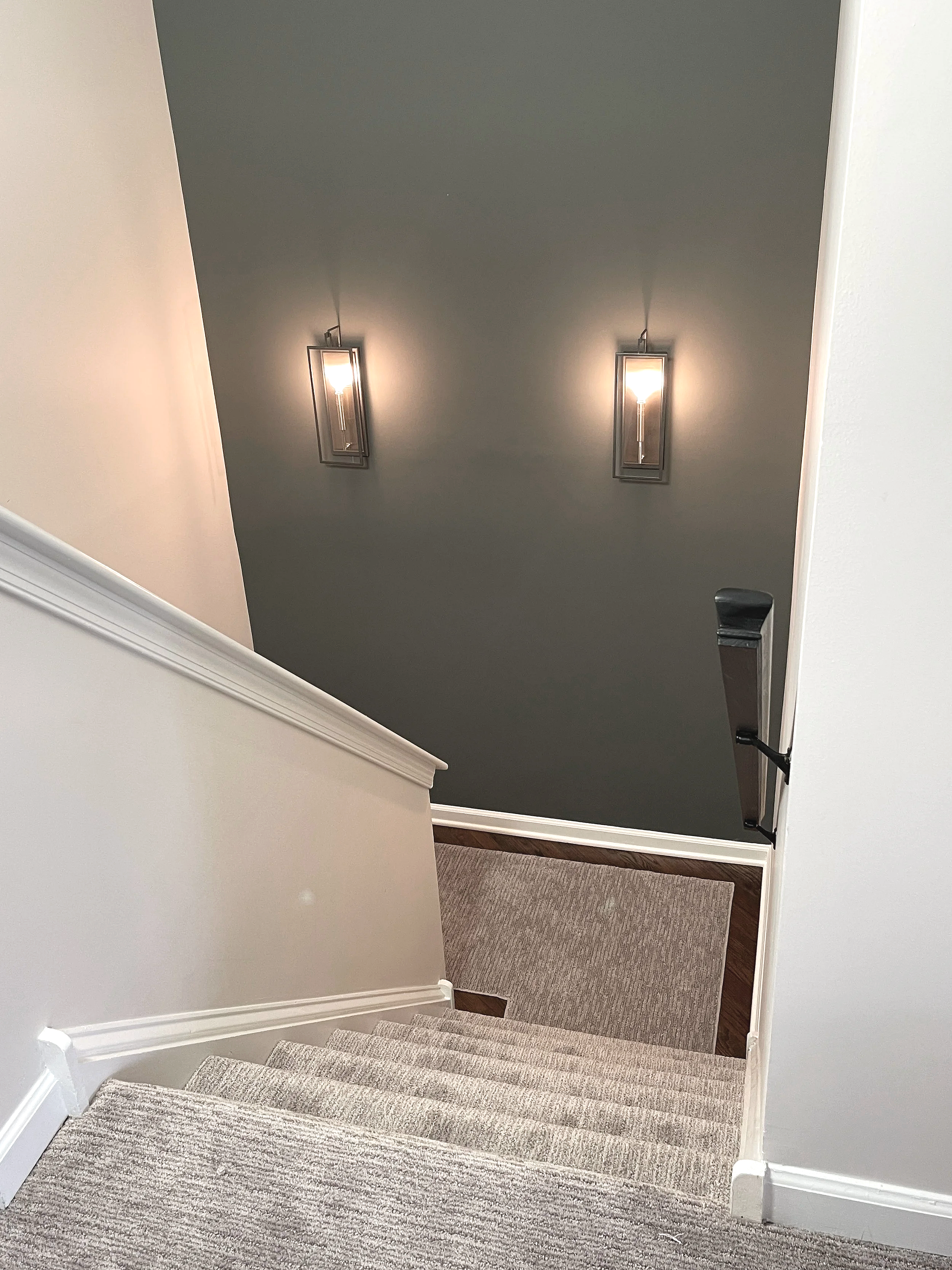 Detail of Night Owl accent wall in a back stairwell with two lantern style sconces for dramatic effect against the lighter surrounding walls.  Custom paint plan and photography by Sara Trotter / Chroma Maison Design. 