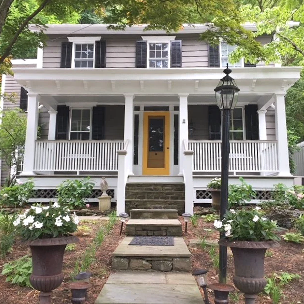 Exterior of a bungalow home with gray wood siding and a rich buttercup yellow accent front door. Custom paint plan and photography by Sara Trotter / Chroma Maison Design.