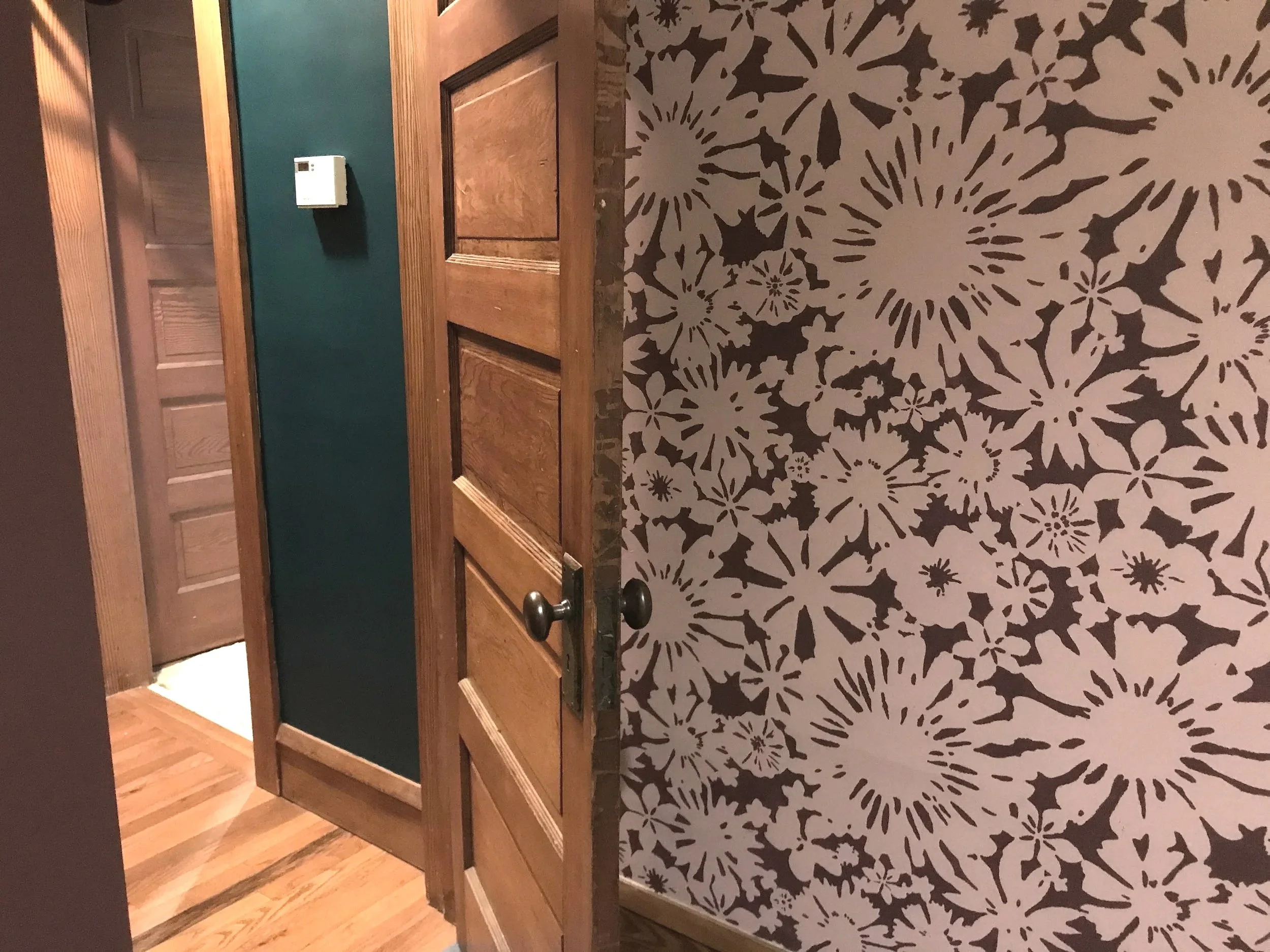 Detail of a hand-painted wall mural of stenciled pink and maroon daisy florals, painted by Sara Trotter.
