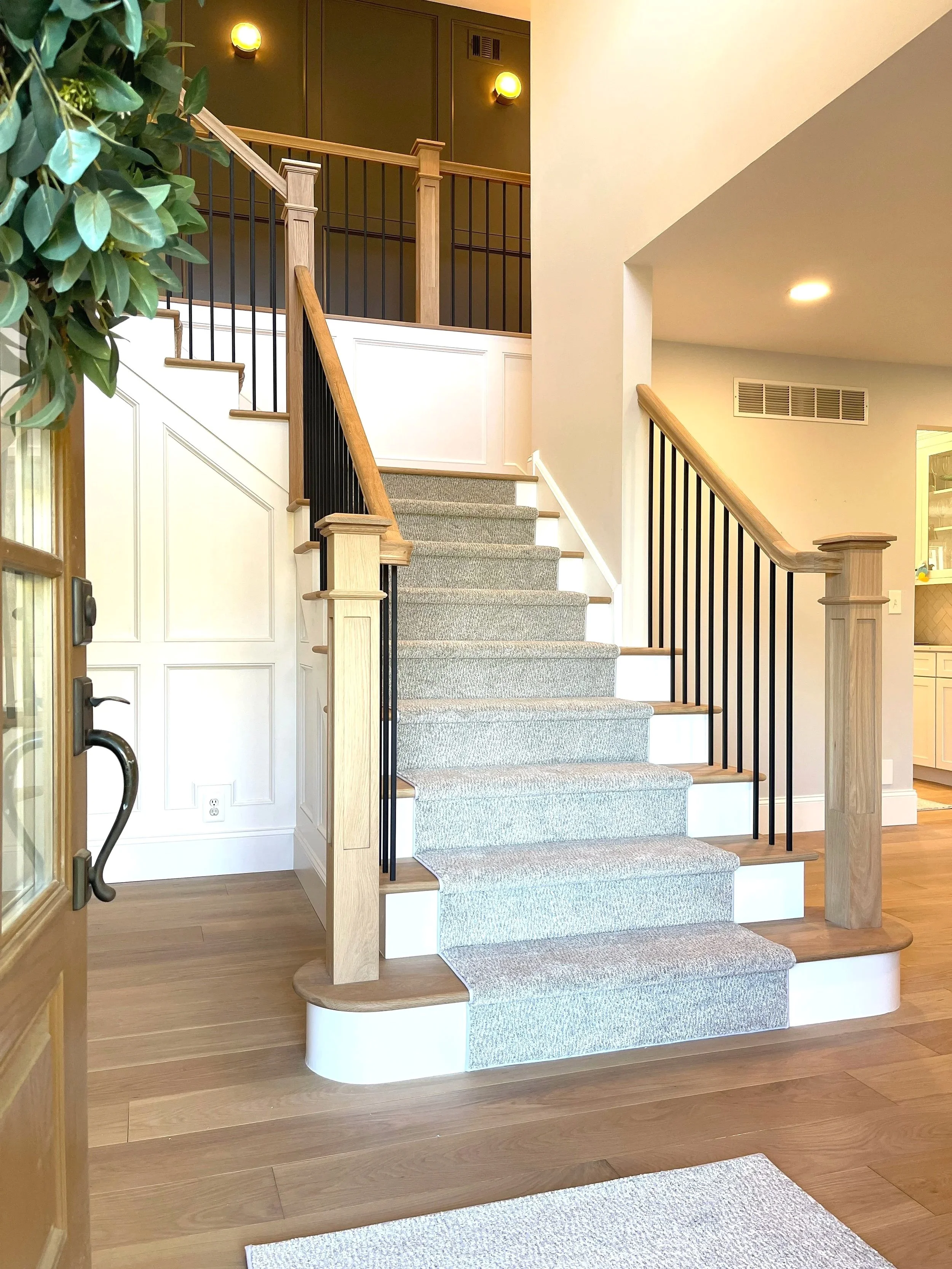 Welcome home!  A beautiful white oak staircase renovation with a custom carpet runner facing the entrance foyer, designed and photographed by Sara Trotter / Chroma Maison Design.