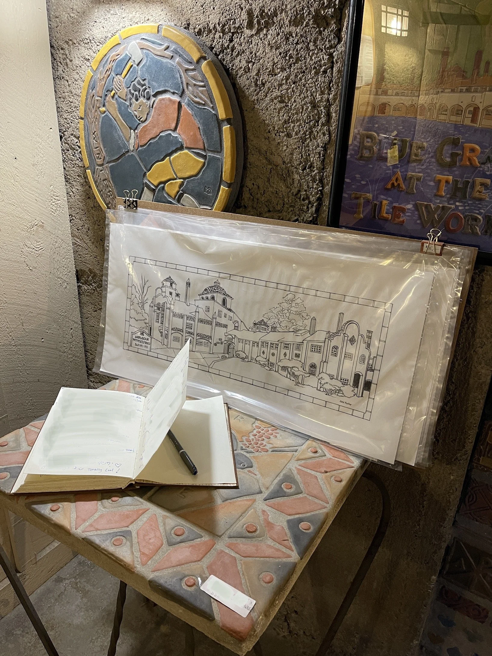 Interior view of a table at The Moravian Tile Works featuring a display of Sara Trotter's prints for sale and an open guest book.  Prints and photography by Sara Trotter / Chroma Maison Design.