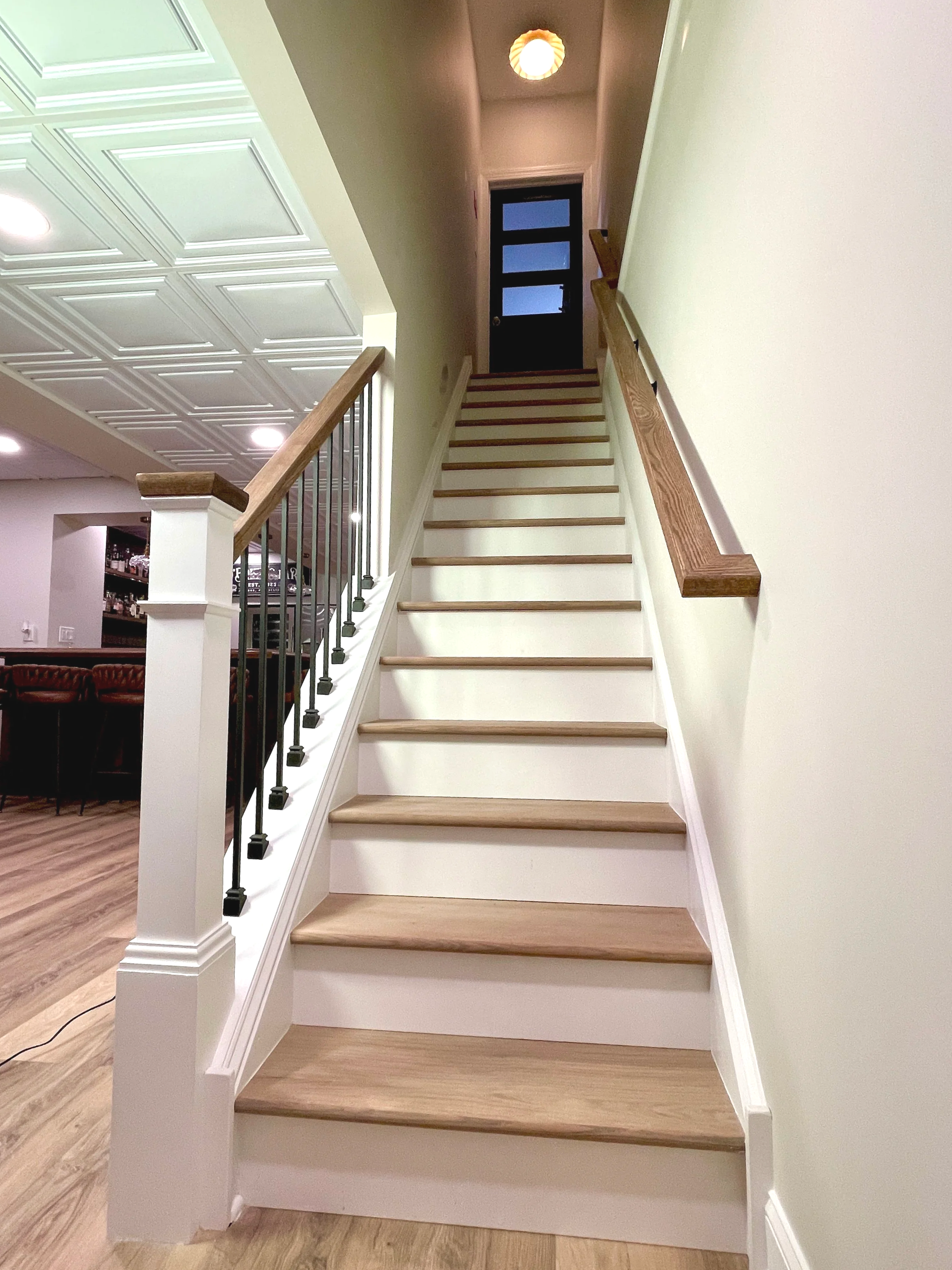 Basement staircase remodel in white oak with black metal interior spindles, designed and photographed by Sara Trotter / Chroma Maison Design.