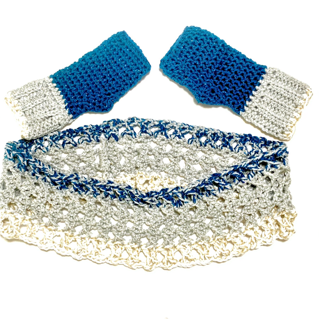 A crochet hat and matching fingerless gloves in white and blue yarn, with the gloves featuring silver accents.