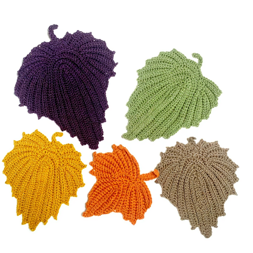 Five colorful crocheted leaves in purple, green, yellow, orange, and beige arranged on a white background.