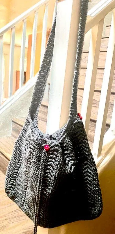 A knitted black and white bag hanging on a staircase railing.