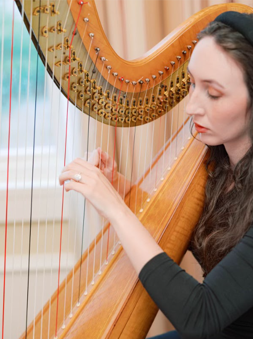A woman playing a harp indoors.