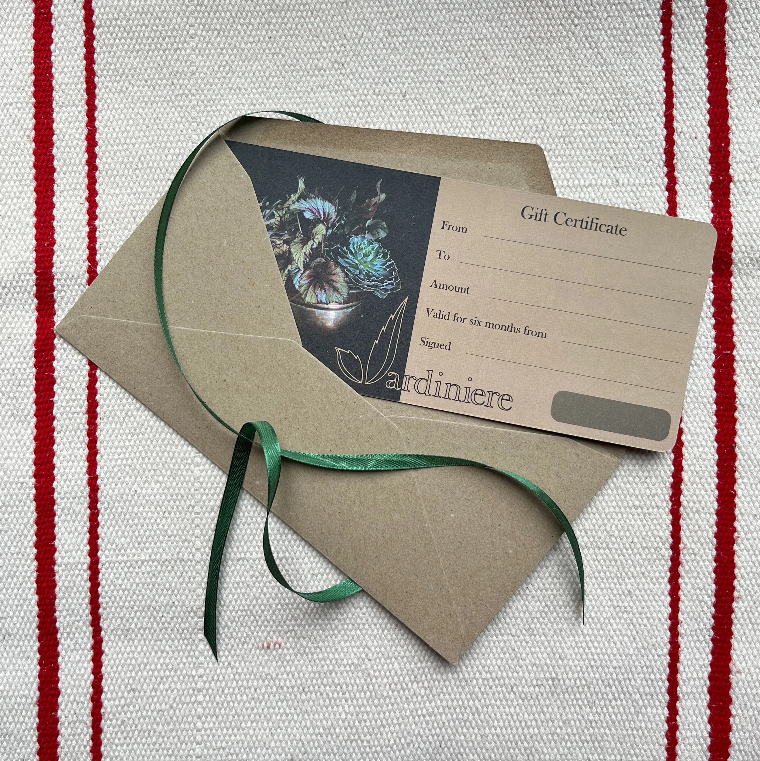 A decorative gift certificate with envelope and ribbon on a festive table cloth
