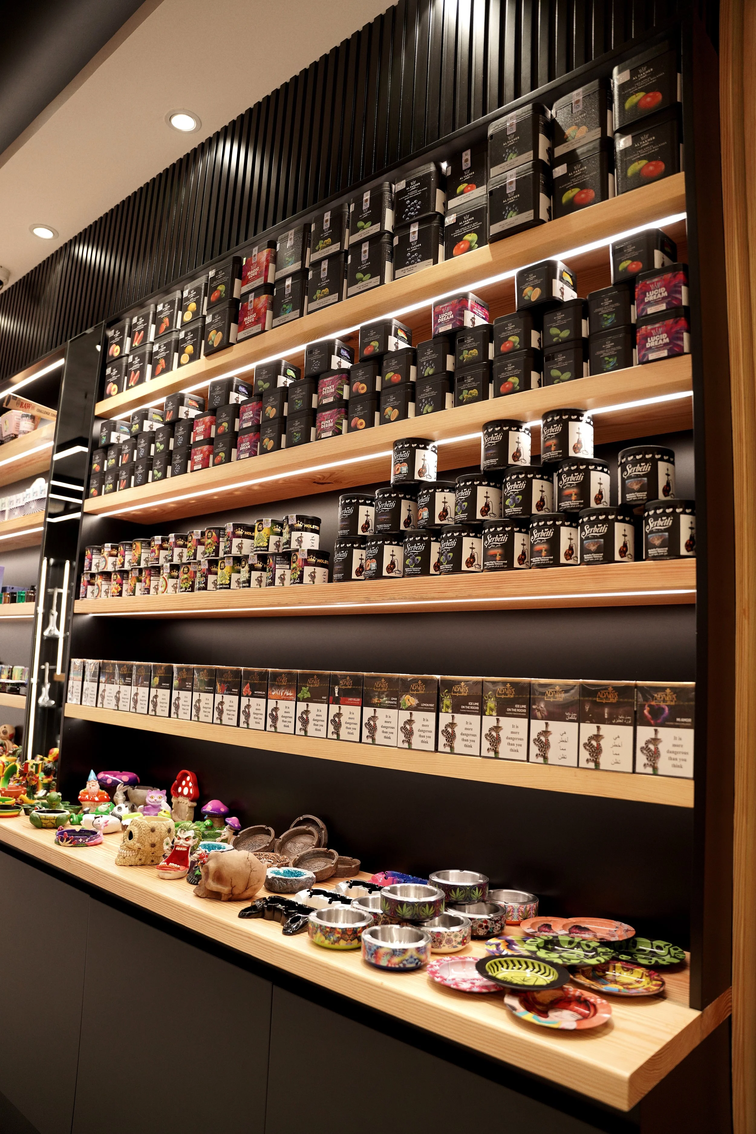 Store shelf displaying various tins of shish or herbal products on wooden shelves
