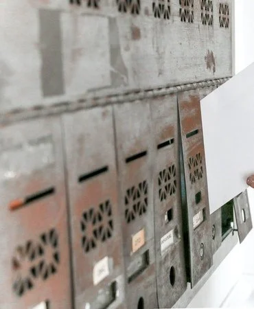 Row of old metal mailboxes on a wall, with some rust and labels.