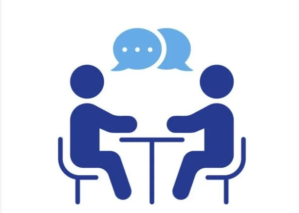 Two people sitting at a table having a conversation, with speech bubbles above their heads.