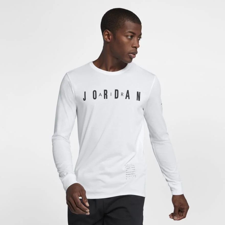 Young man wearing a white long-sleeve Jordan shirt and black pants, looking to his right against a plain light background.