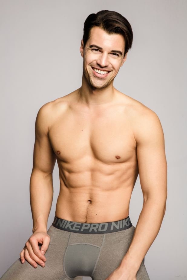 A shirtless man with dark hair smiling against a plain gray background, wearing gray Nike Pro underwear.