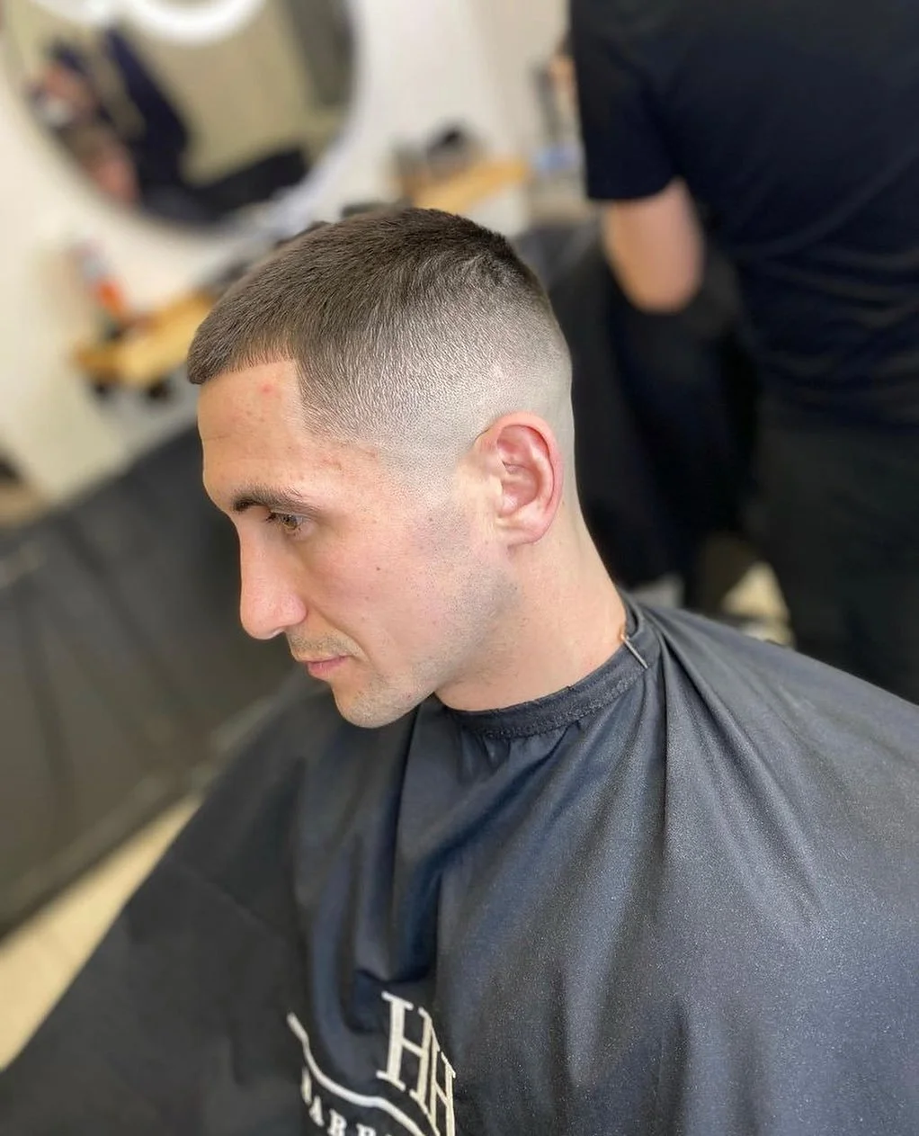 Man with a fresh fade haircut sitting in barber's chair at a barbershop.
