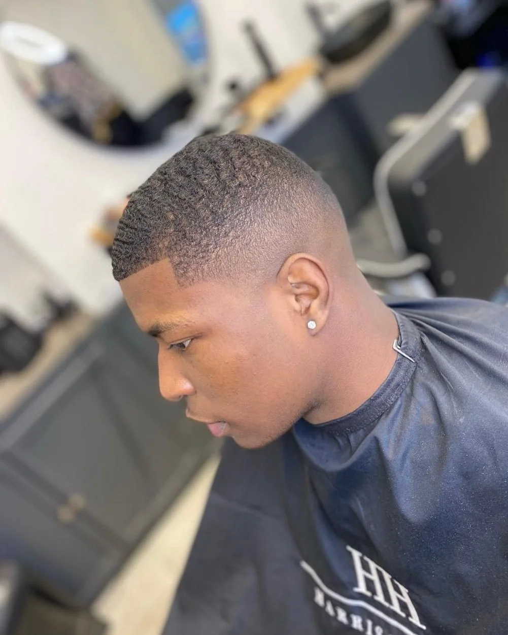Young man with a fresh fade haircut sitting in a barbershop chair.