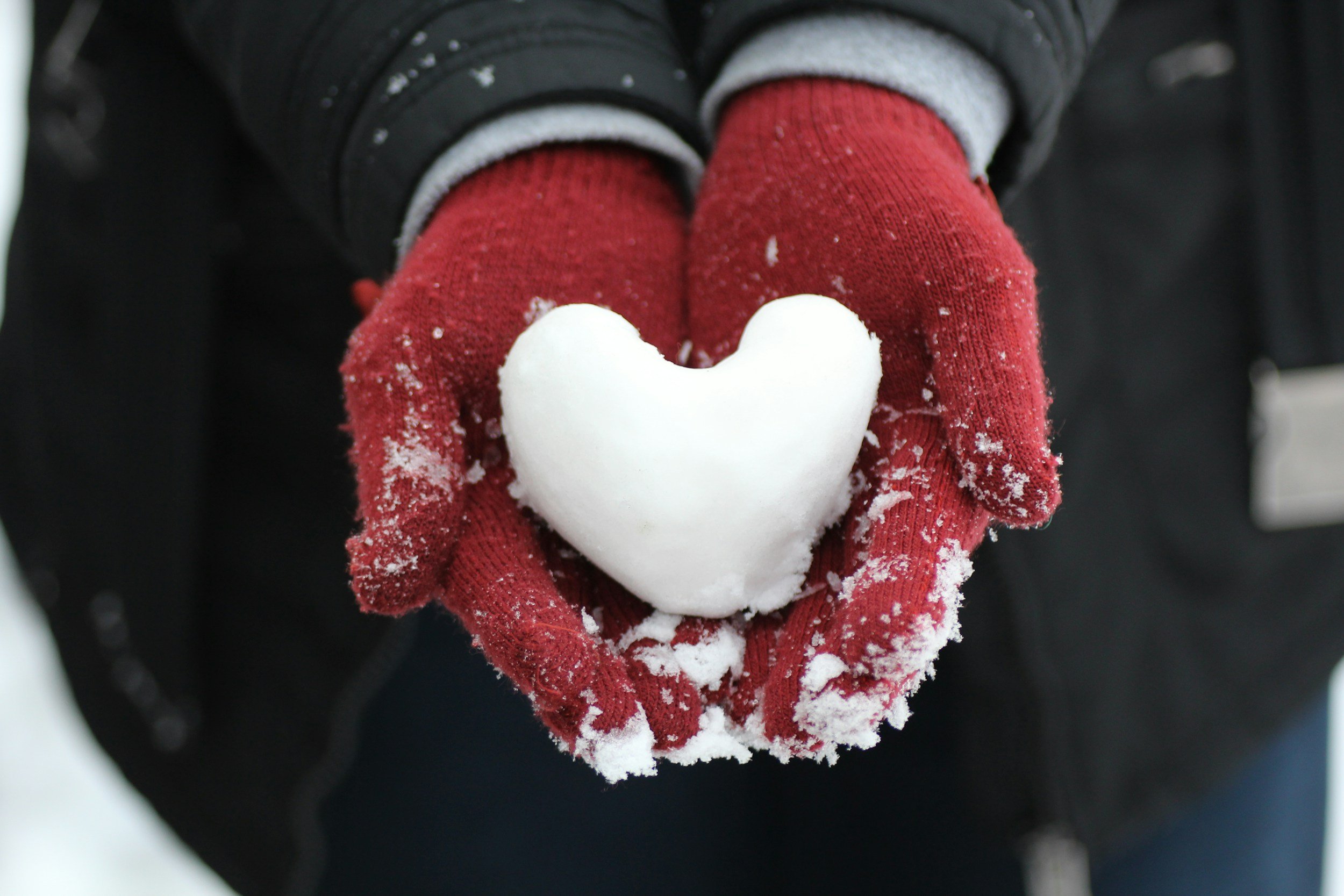 Red gloves holding a snow heart
