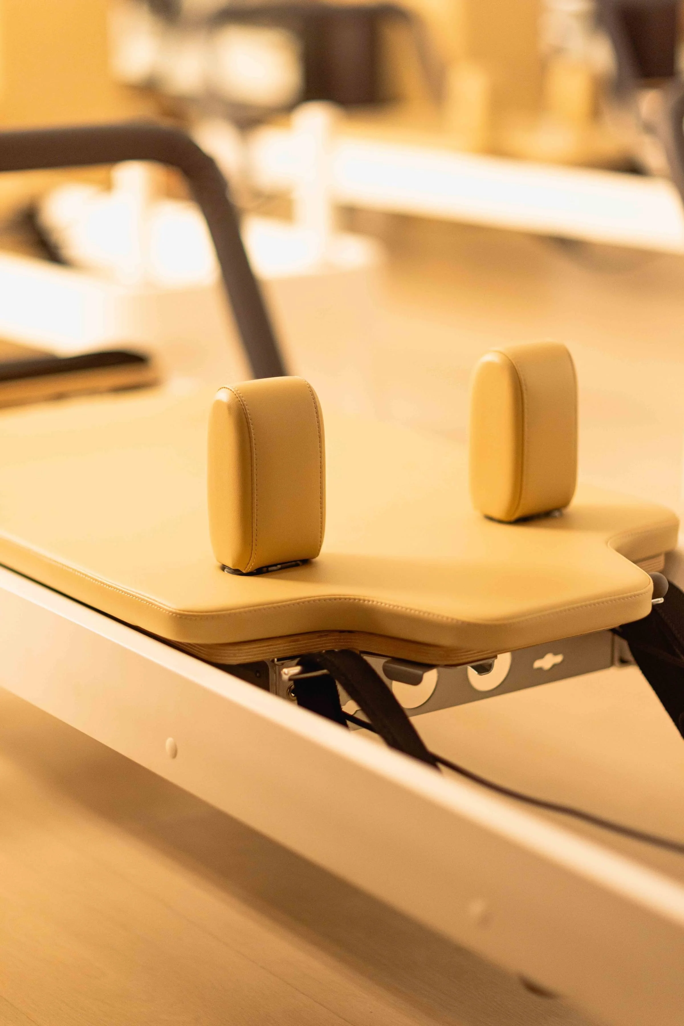 A beige-colored specialized surface with two vertical cushioned head supports on a pilates reformer 