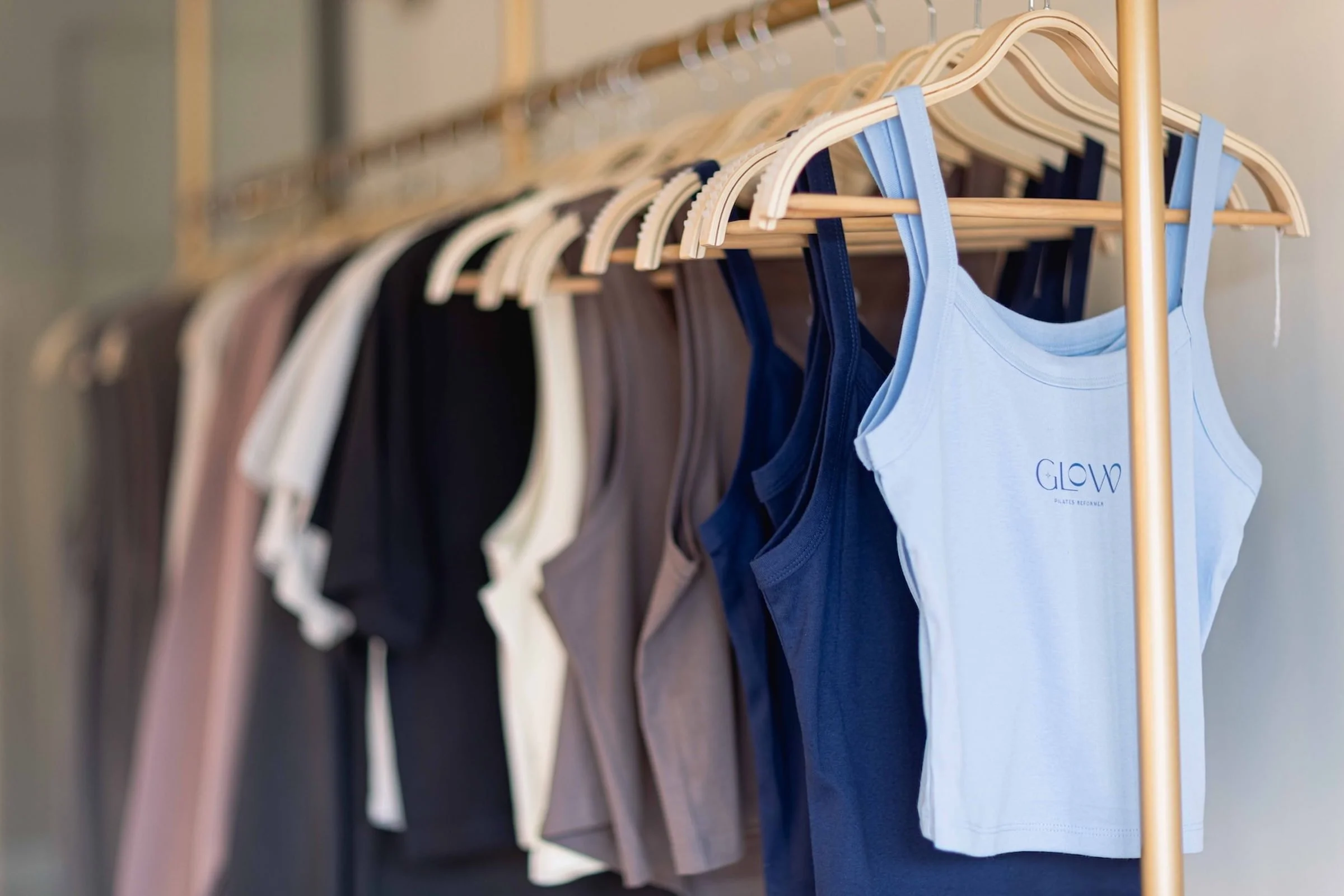 Newly hung tank tops in various colors on wooden hangers on a clothing rack