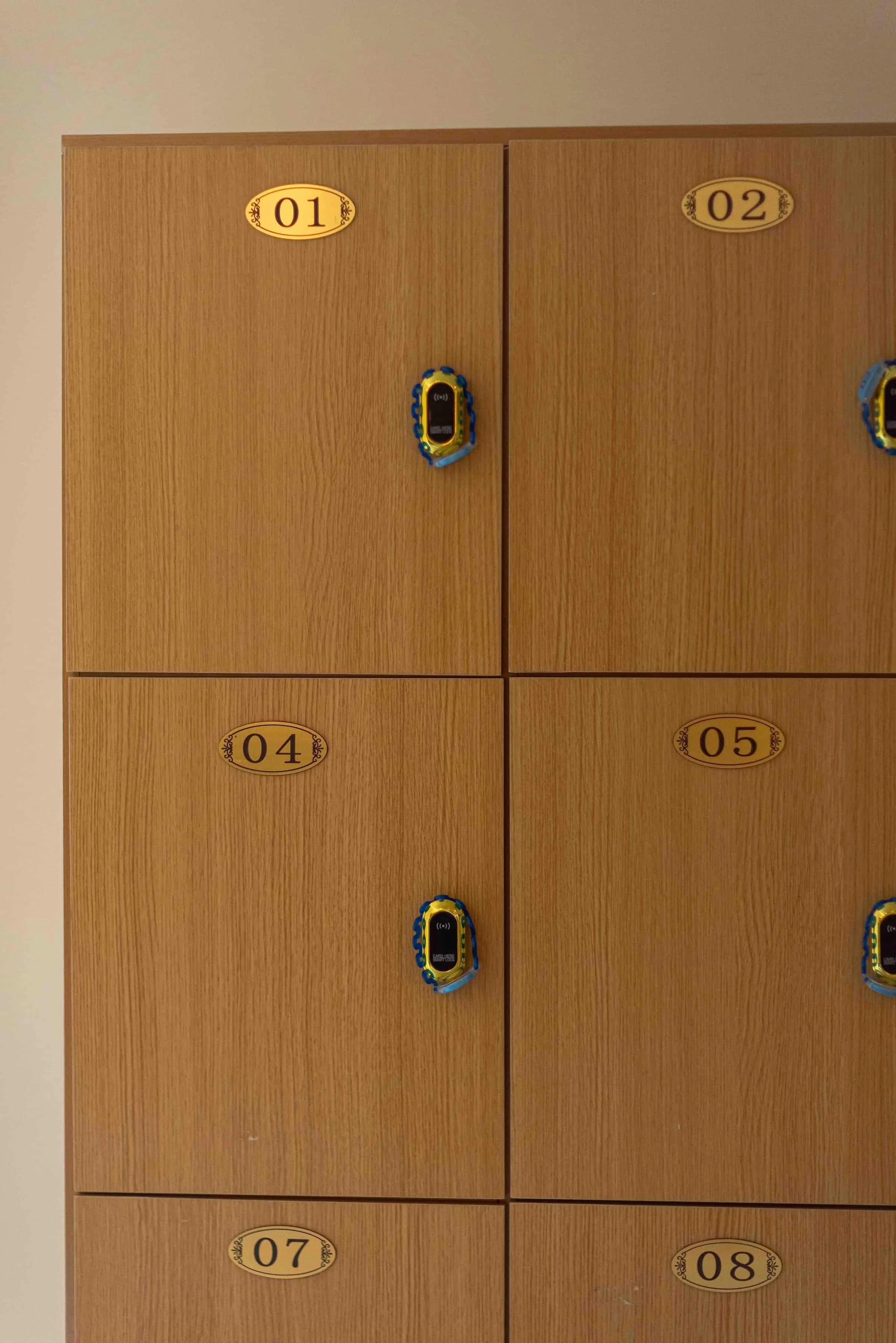 Wooden lockers numbered 01, 02, 04, 05, 07, and 08 with combination locks.