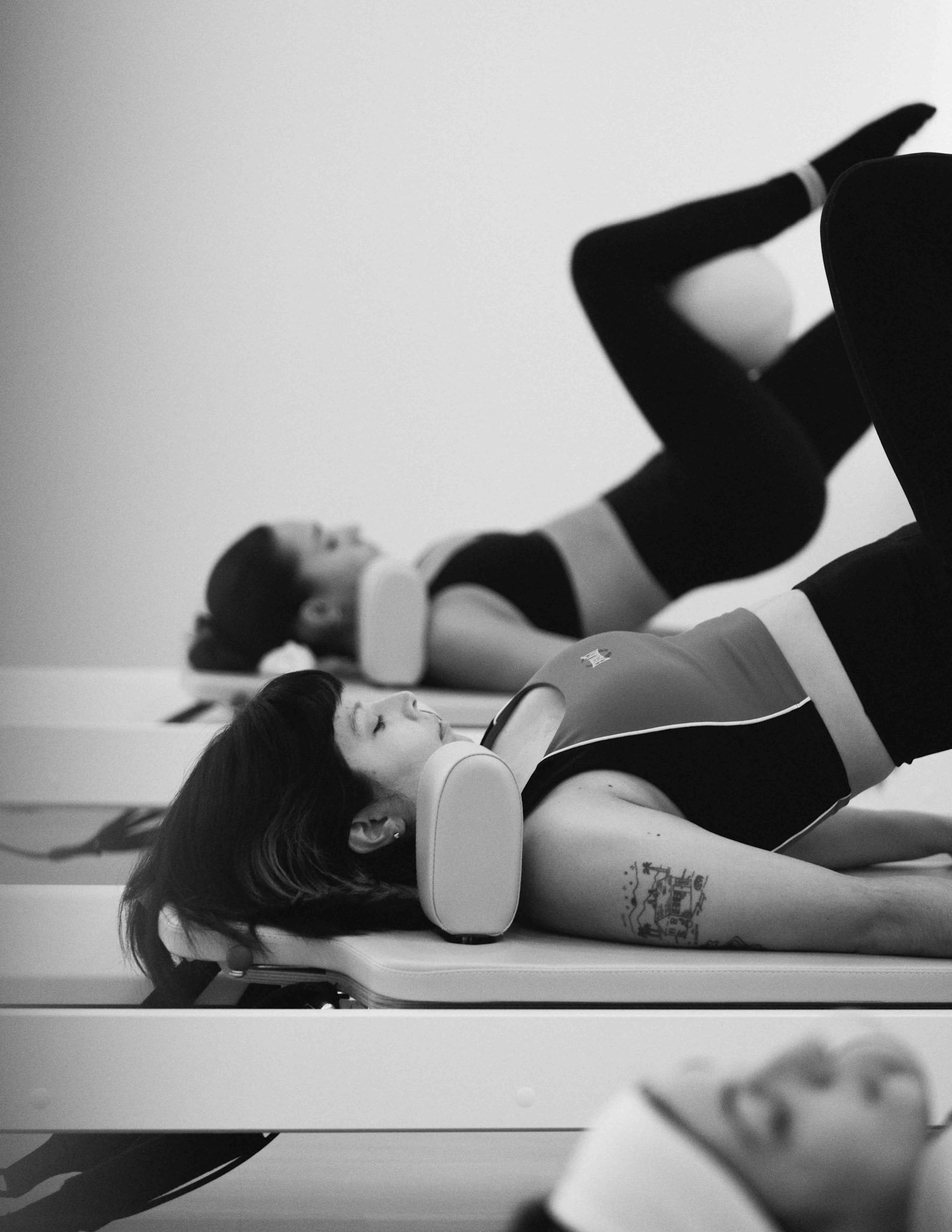 Two women lying on separate massage tables, receiving neck and shoulder massages with their eyes closed, in a wellness or massage therapy session.