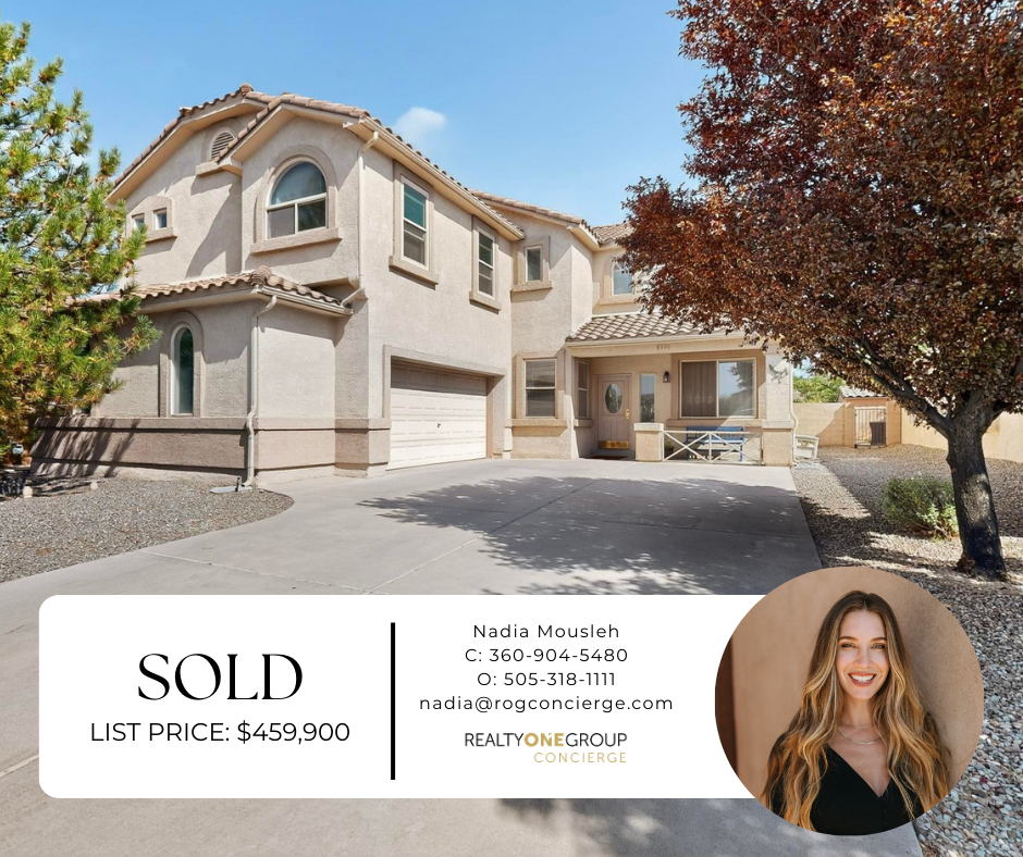 A two-story house with a beige stucco exterior, tiled roof, and multiple windows, featuring a concrete driveway and landscaping with trees and small bushes - Nadia Mousleh Real Estate