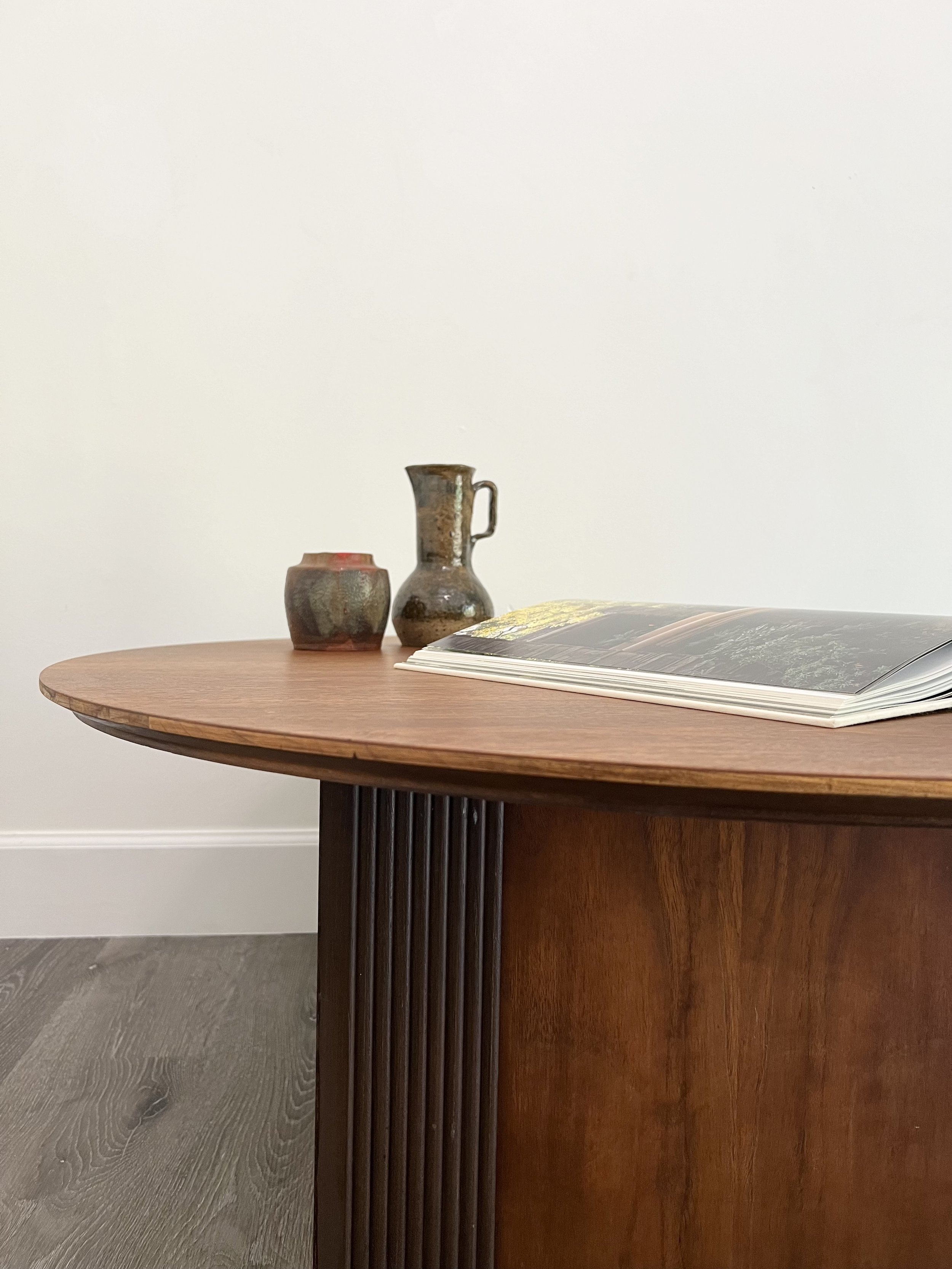 A wooden table with a book, a ceramic container, and a ceramic pitcher on top.