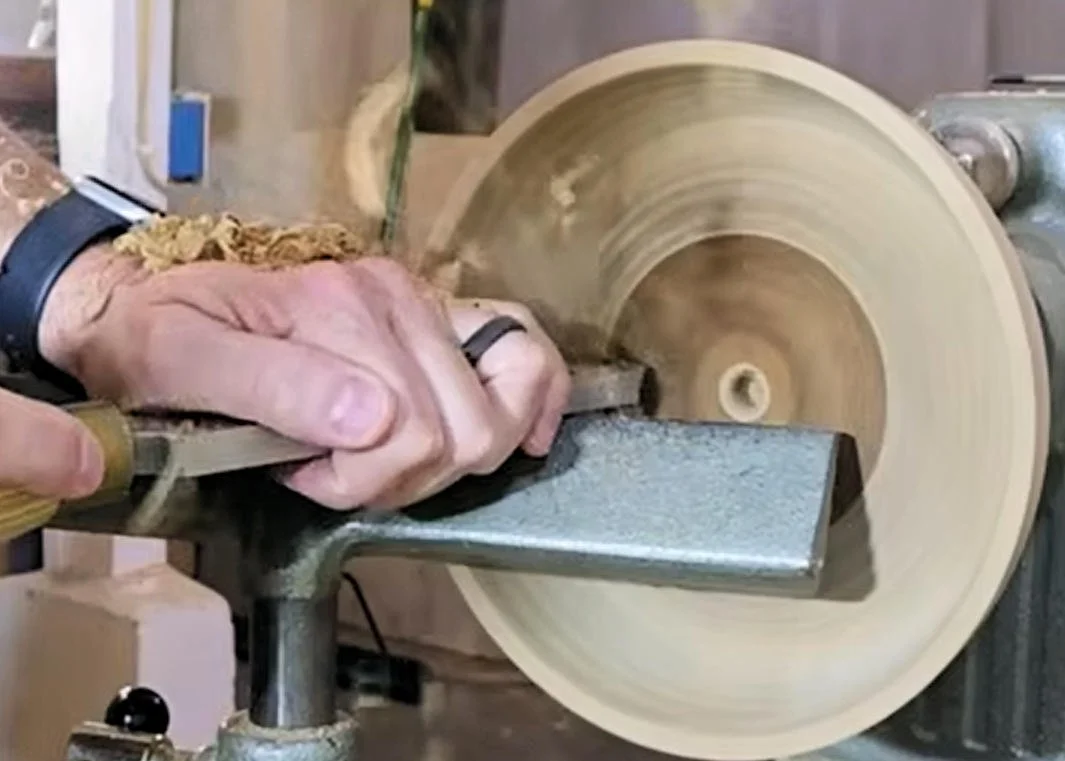 Bowl scraper refining the inside surface of a wood bowl.