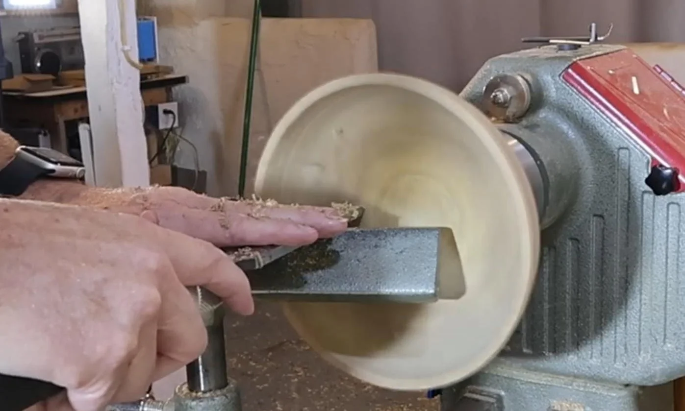 Negative rake scraper refining the inside surface of a wood bowl.