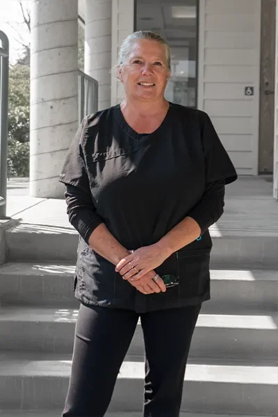 A smiling woman standing on outdoor steps in front of a building.