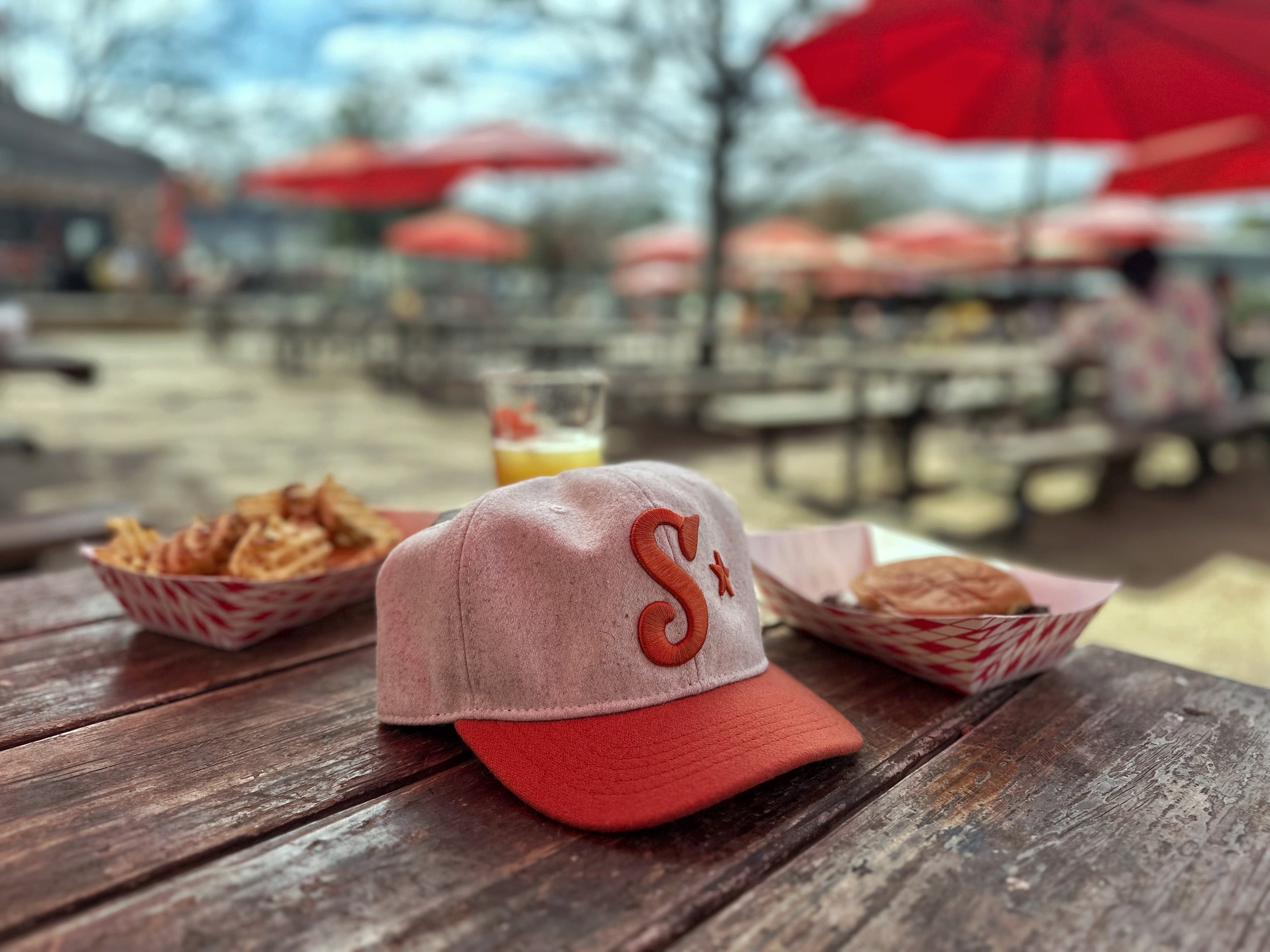 Cream and orange Southside Heritage wool golf hat on an outdoor table in Austin