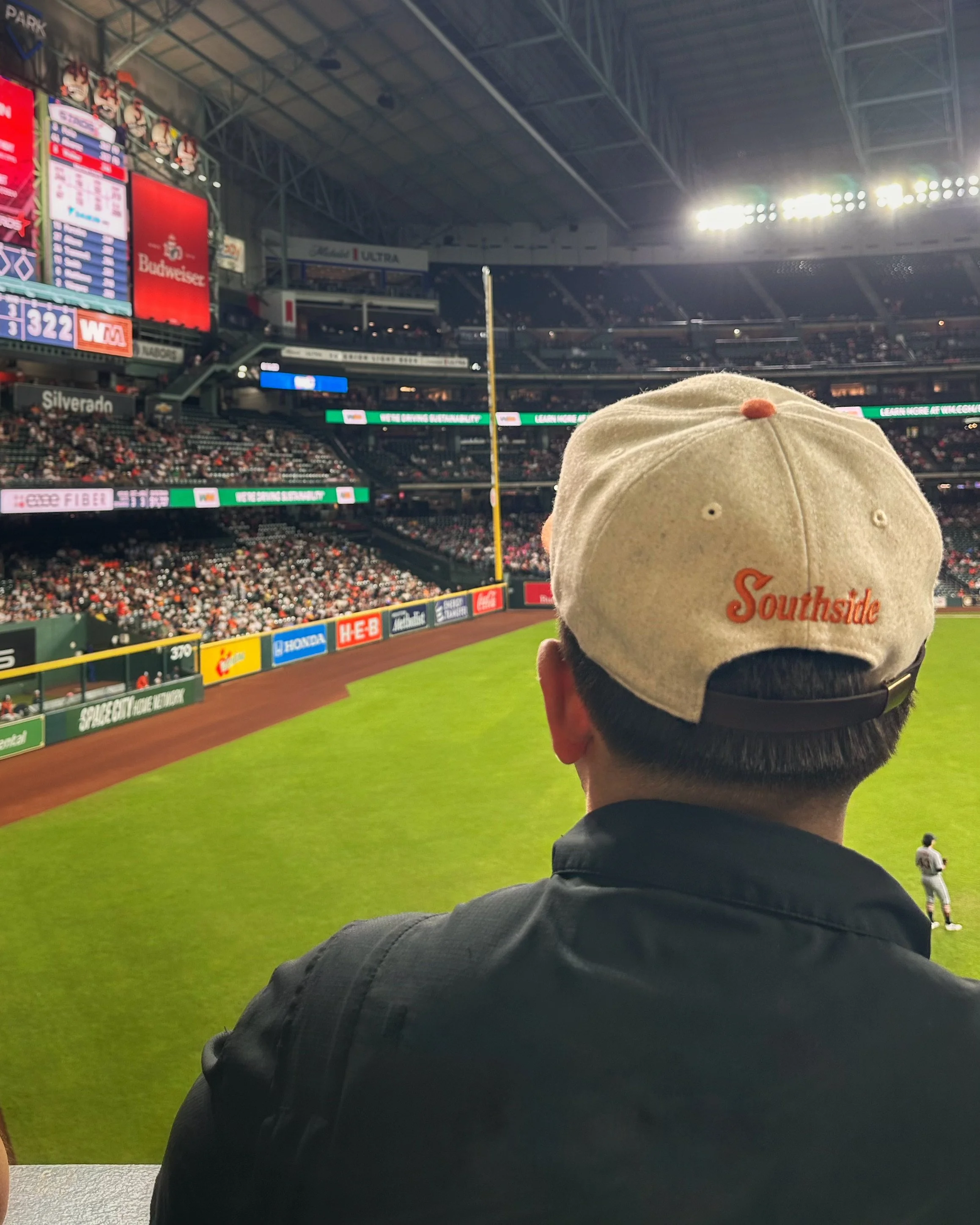 Person wearing a cream and orange Southside Heritage wool cap at a astros baseball game