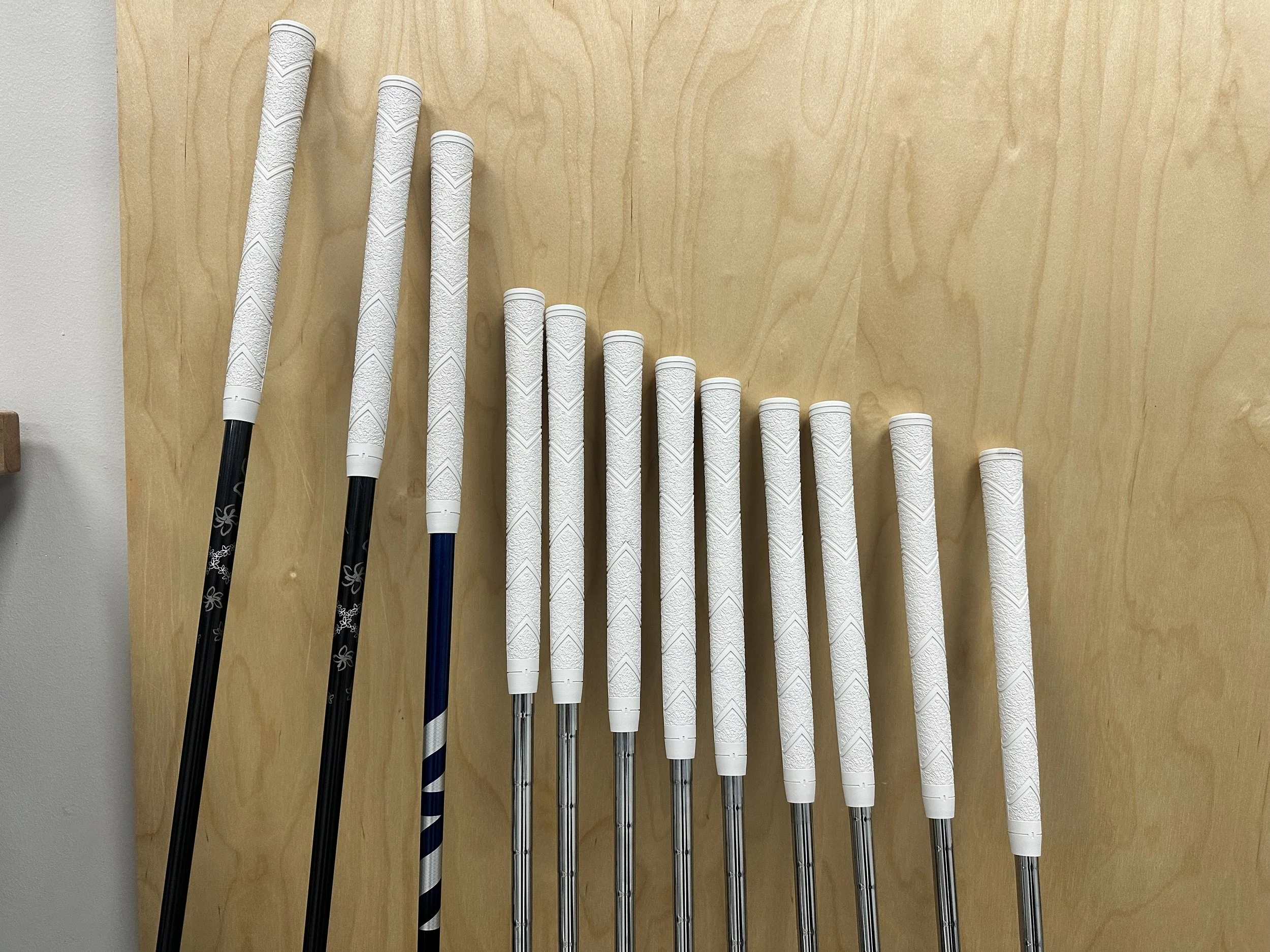 Freshly regripped golf clubs with new white grips at Southside Golf Co in South Austin