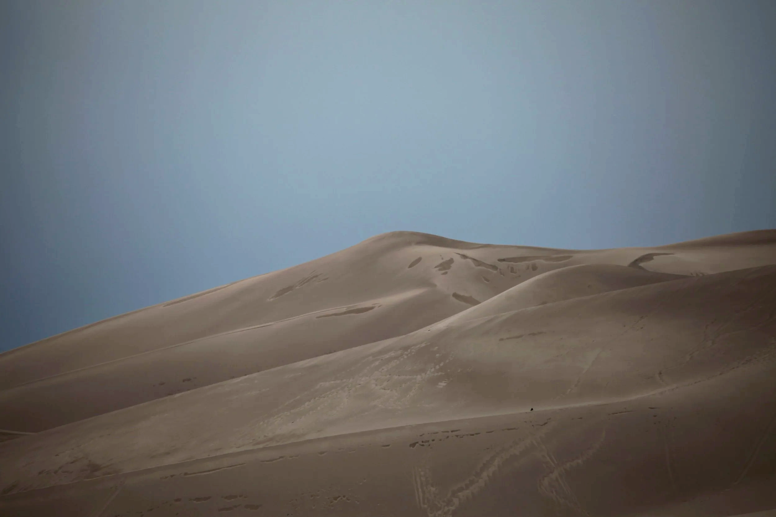 Sand dunes under a clear blue sky.