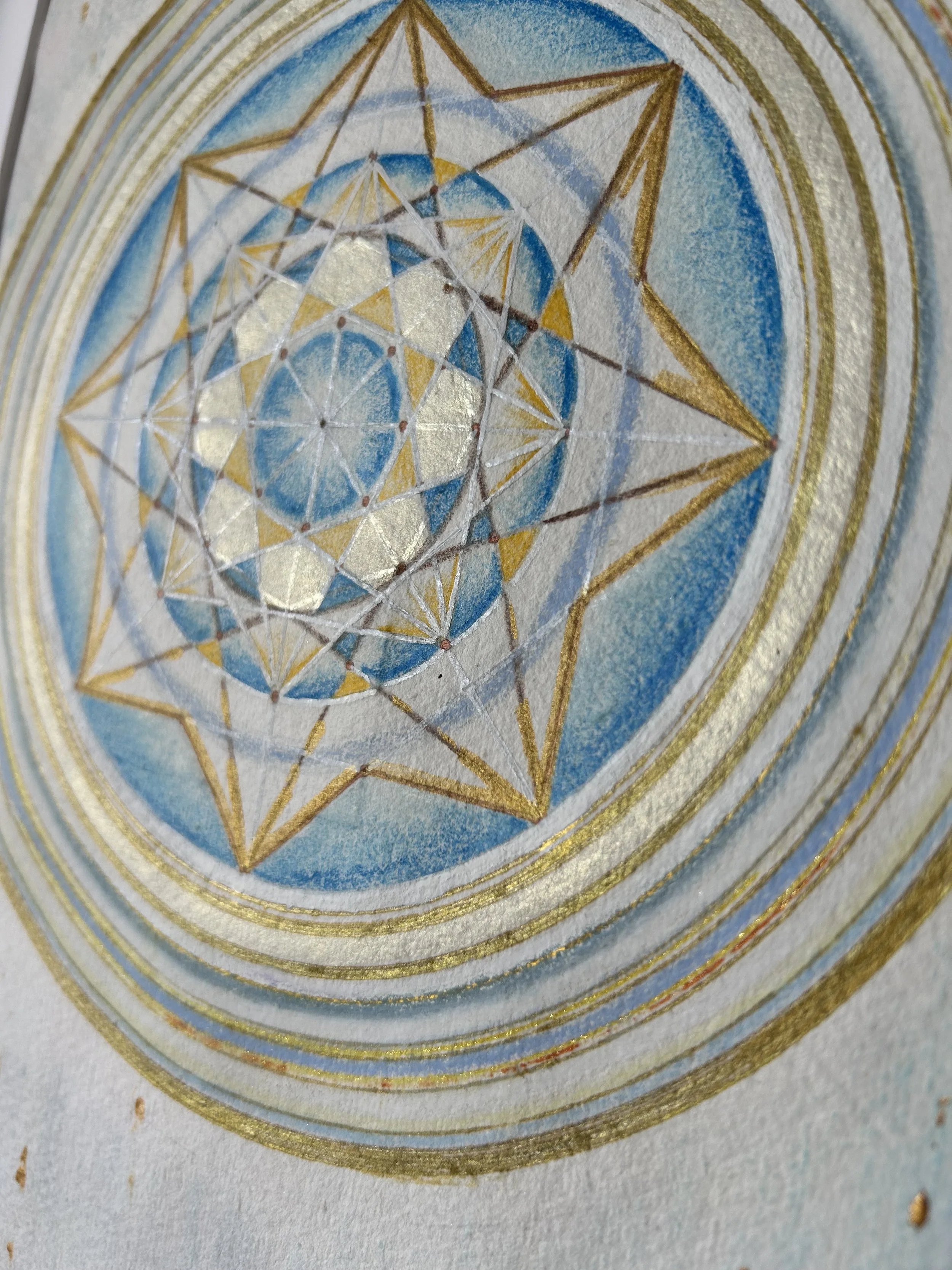 Ein kunstvolles Mandala mit geometrischen Mustern in Blau, Weiß und Gold. Mittelpunkt ist eine komplexe, symmetrische Struktur, umgeben von konzentrischen Kreisen und goldenen Linien.