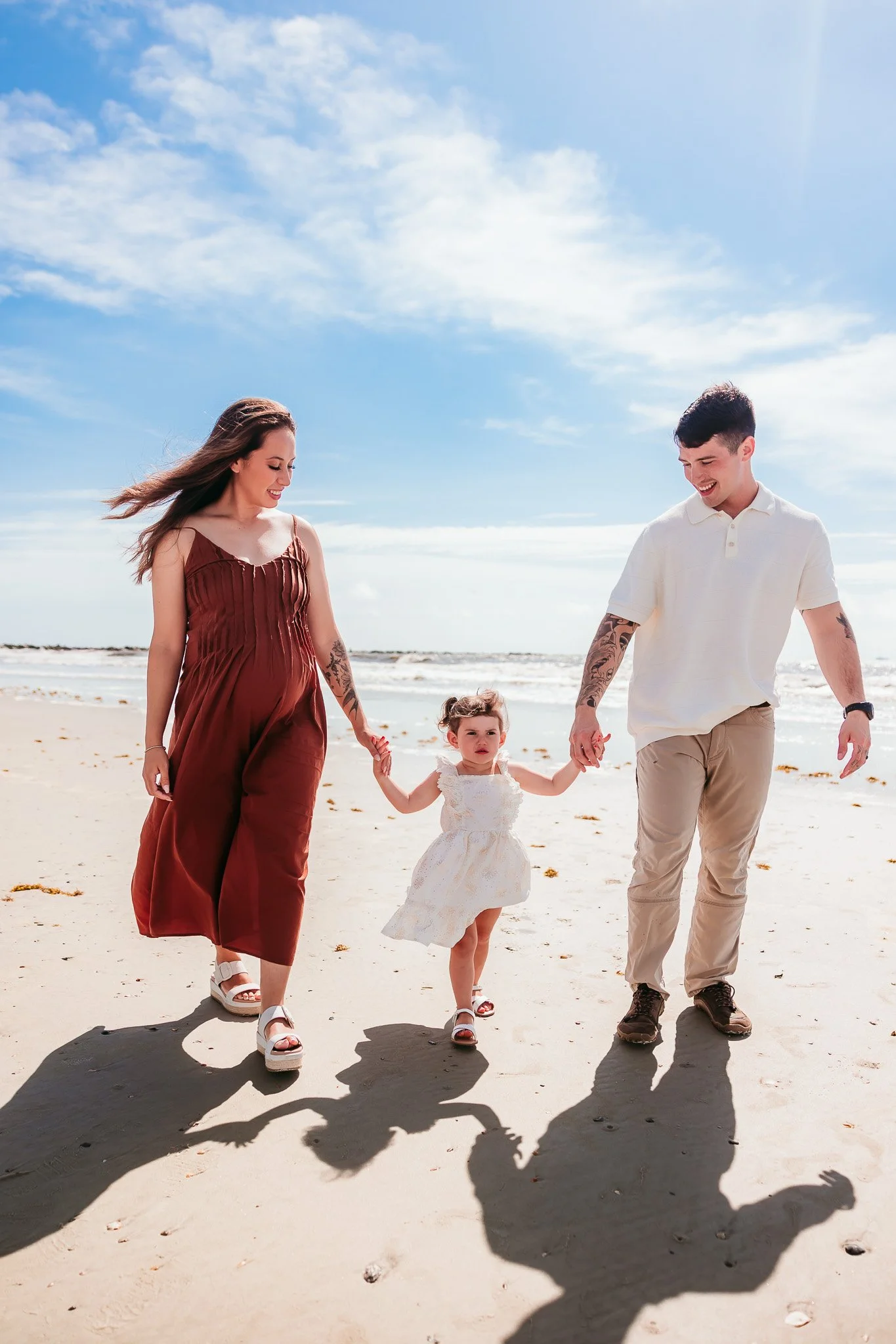 Parents walking hand in hand with their toddler during a beach maternity photography session in Jacksonville, Florida.