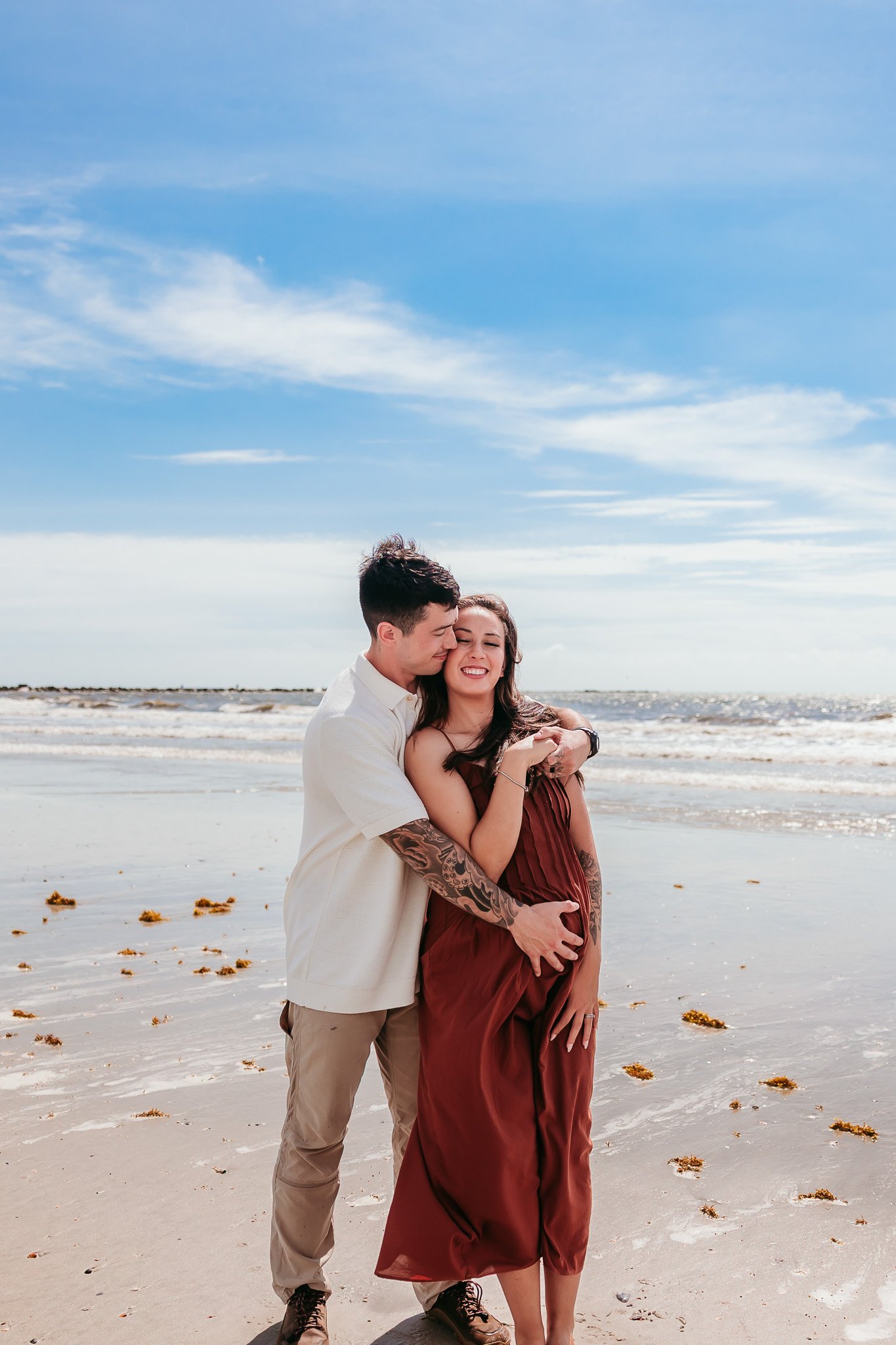 Growing family embracing together during a lifestyle maternity photography session on Jacksonville Beach.