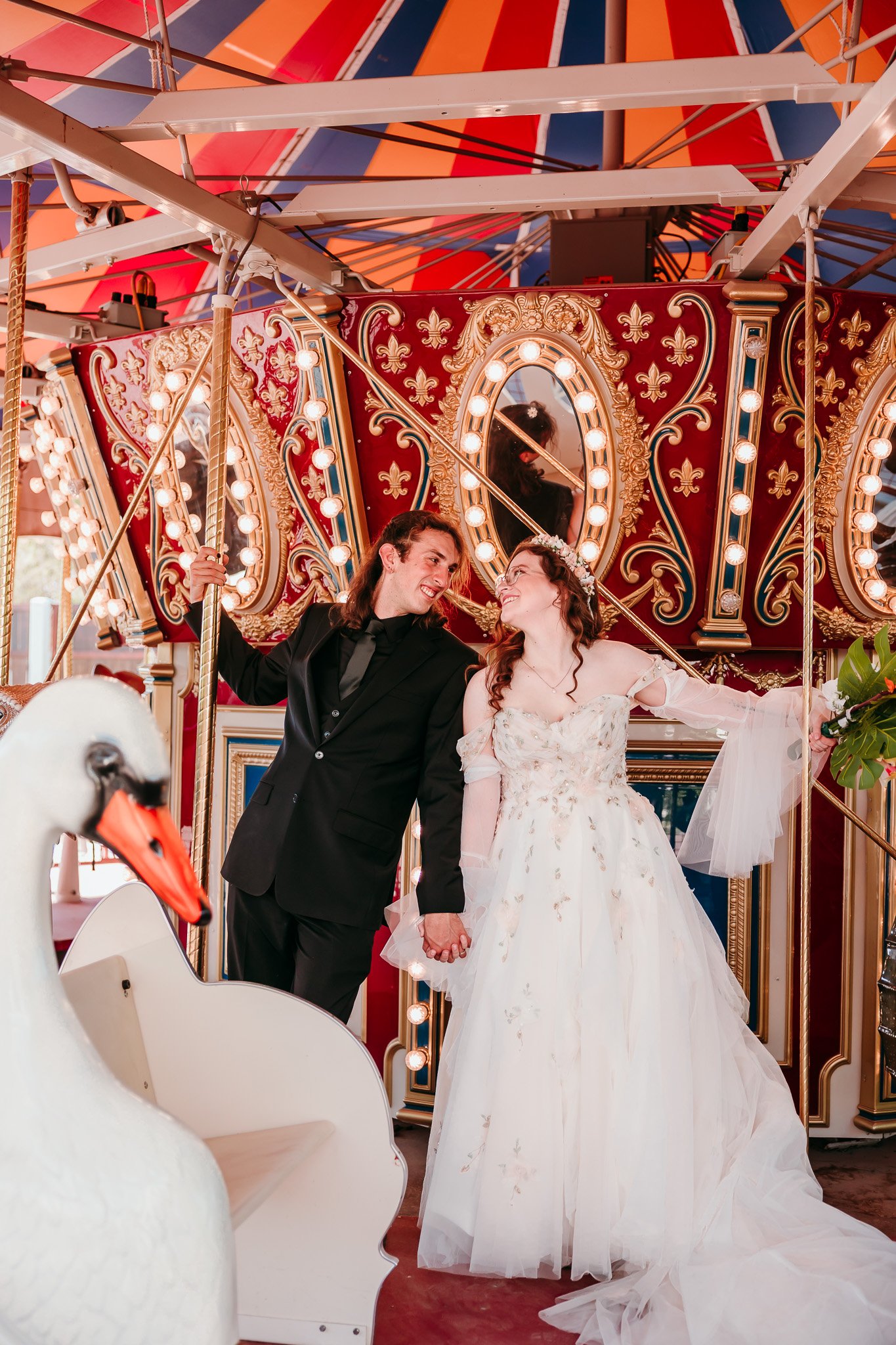 Bride and groom holding hands while riding the carousel during their El Paso Zoo wedding in El Paso, Texas.