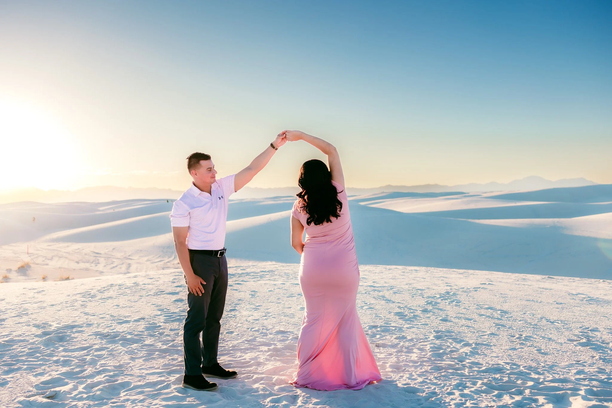 Expecting parents dancing together on the dunes during a romantic maternity photography session at White Sands National Park.