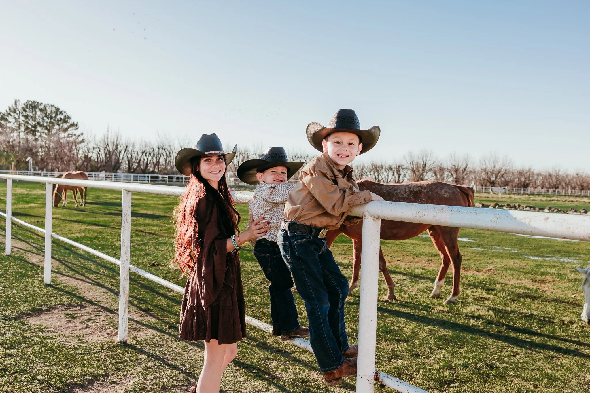 Mother hugging her children beside horses during a western family photography session in La Mesa, New Mexico.