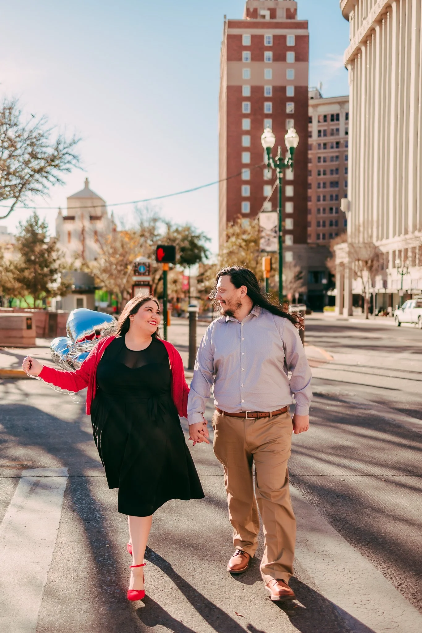 Engaged couple walking hand in hand through downtown El Paso during a romantic urban engagement photography session.