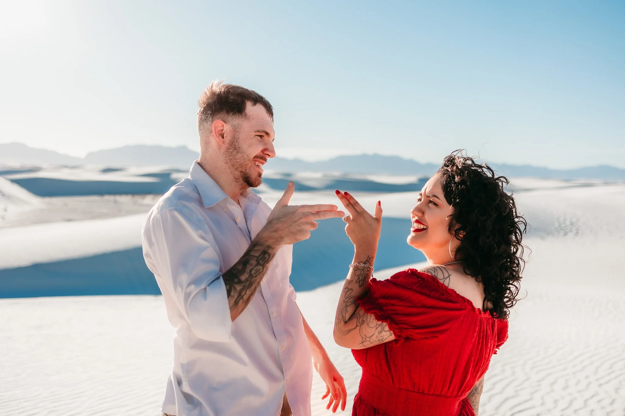 Couple laughing together during a playful engagement session at White Sands National Park in New Mexico.