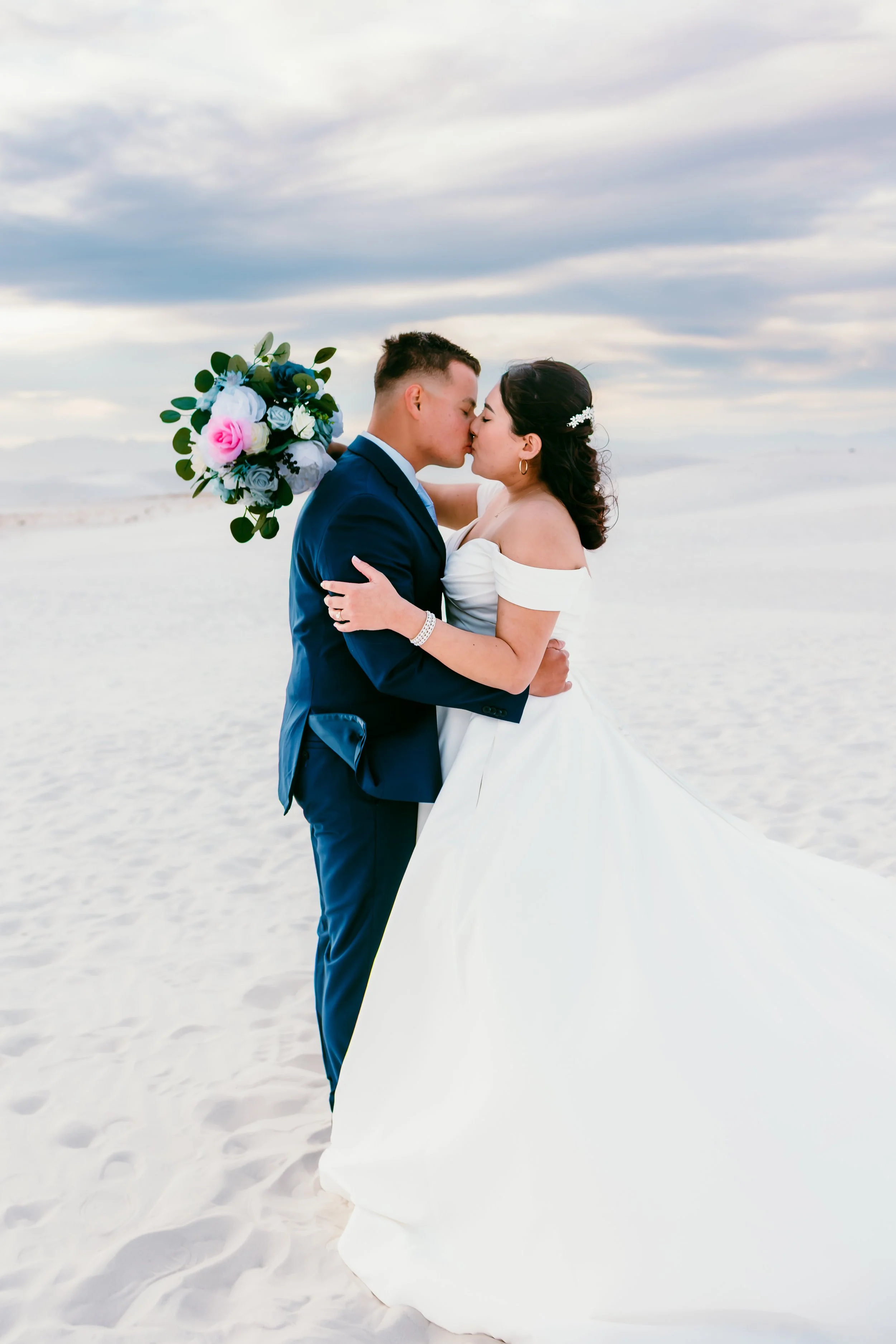 Bride and groom sharing a sunset kiss among the white gypsum dunes at White Sands National Park in New Mexico.
