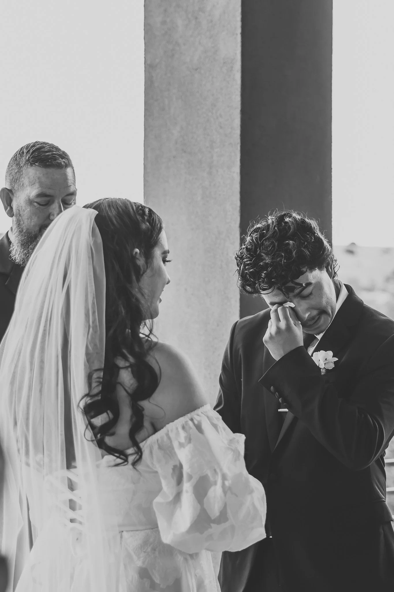 Groom wiping tears away after bride walks down isle