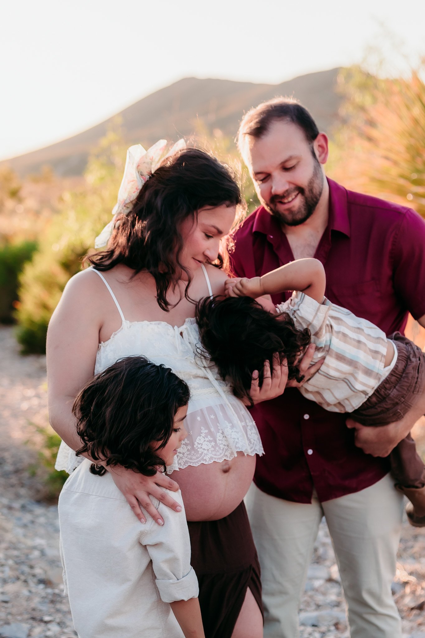Growing family sharing a joyful moment during a maternity photography session in the El Paso mountains.