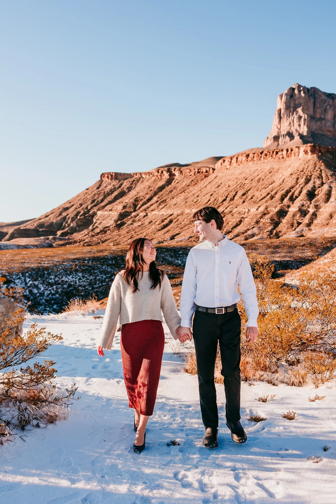 Couple walking hand in hand after their surprise engagement with scenic Guadalupe Mountains views near Carlsbad, New Mexico.
