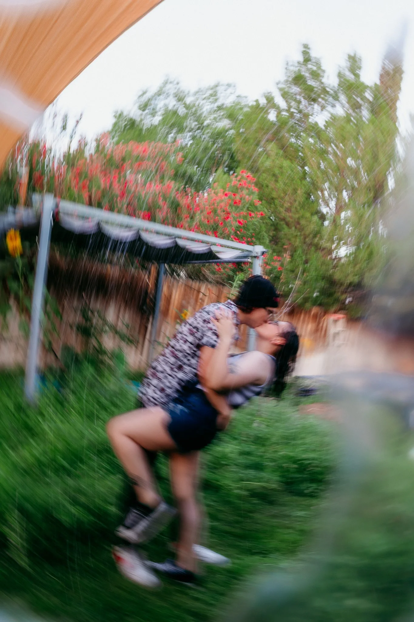 Partners embracing and laughing together during a playful backyard couples session at their Las Cruces home.