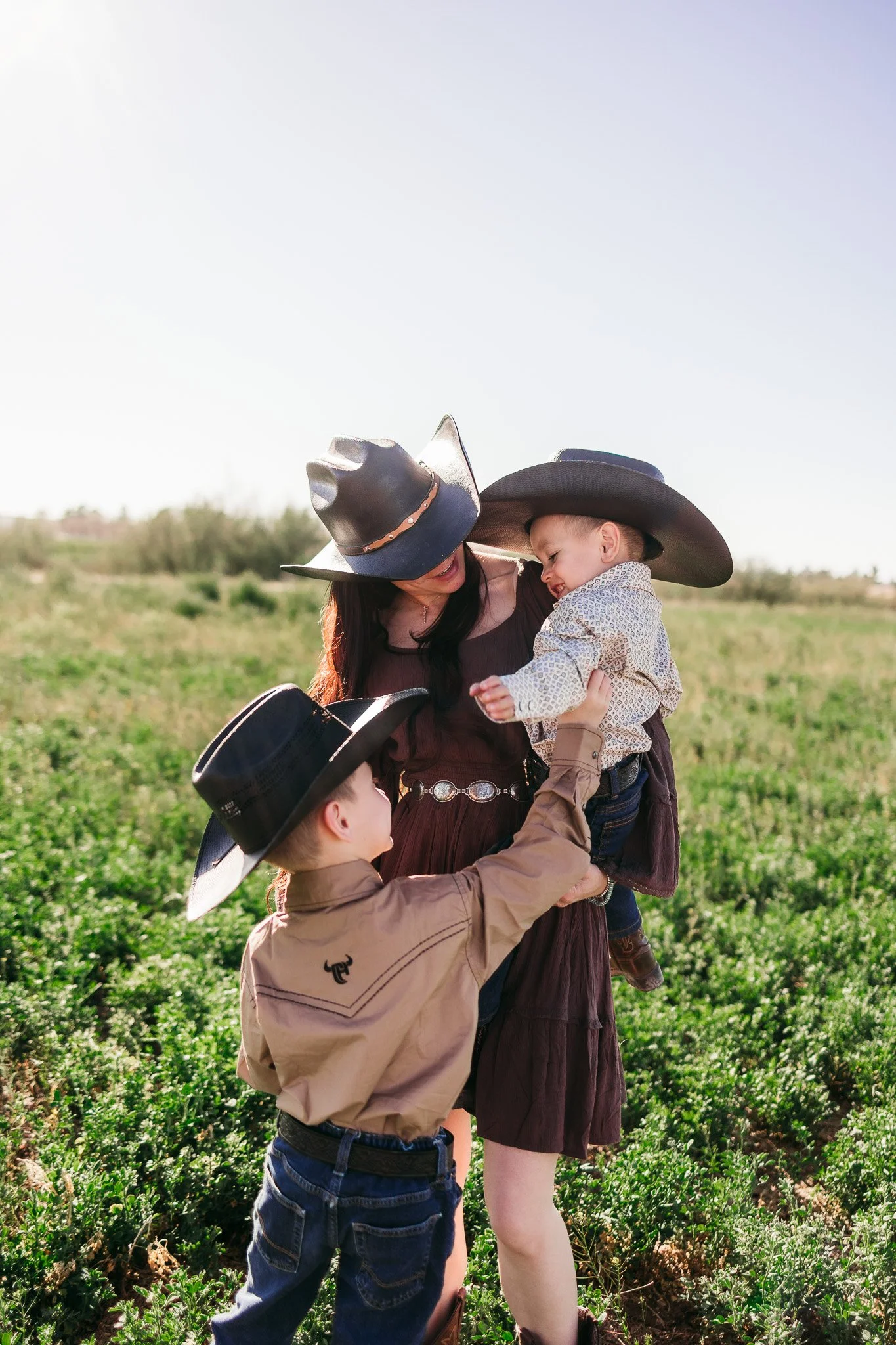 Cowboy family portrait beside a pasture fence during a western lifestyle family photography session in La Mesa, New Mexico.